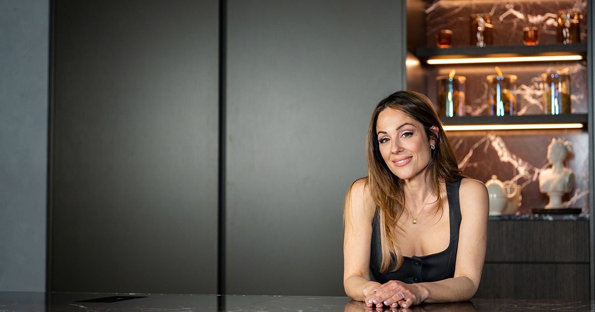 Woman seated at a kitchen island in a dark contemporary kitchen