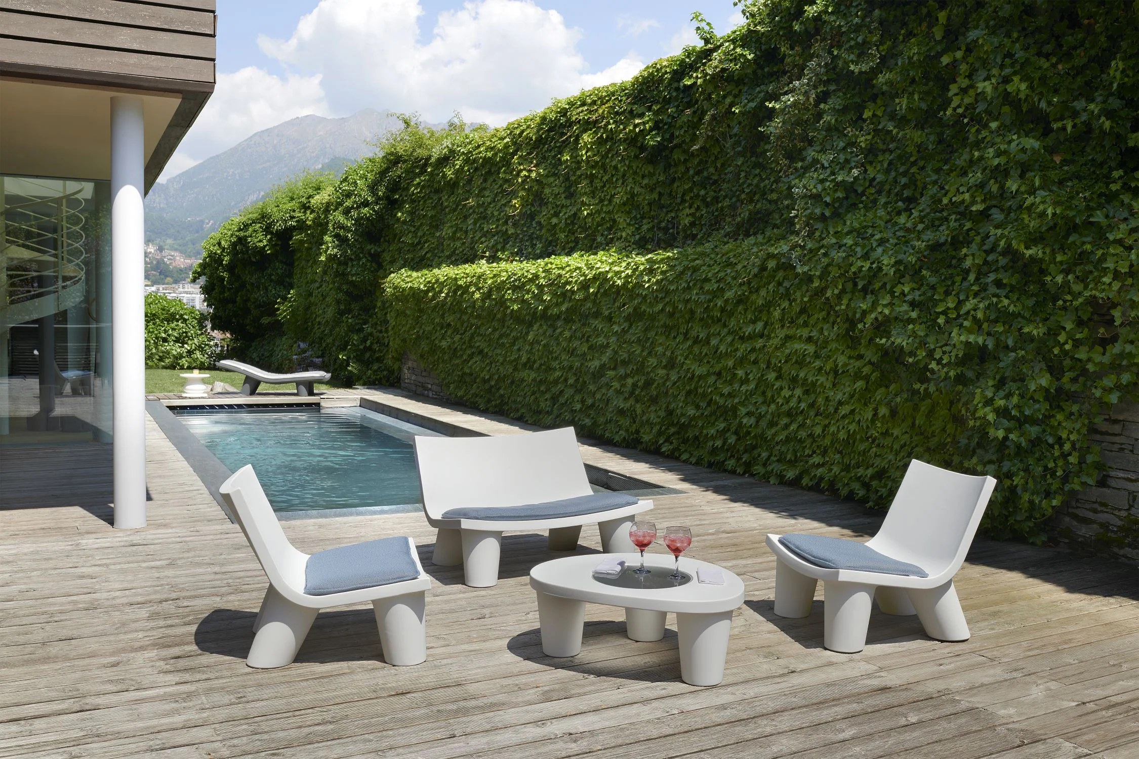 Slide outdoor seating on a poolside terrace with white sculptural furniture